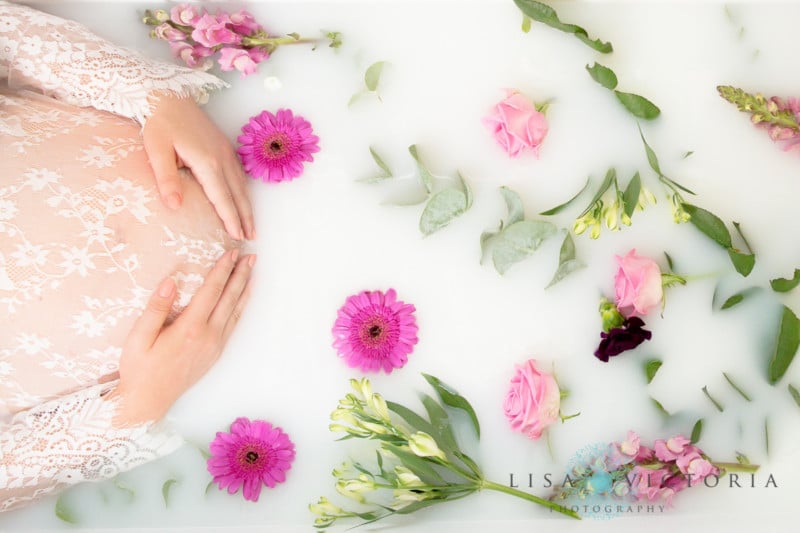 A milk bath photo with a woman's hands holder her pregnant belly